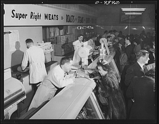 Meat rationing preview. Harold Rowe, Office of Price Administration (OPA) food rationing chief, sells meat to girl reporter at shopping preview of new program