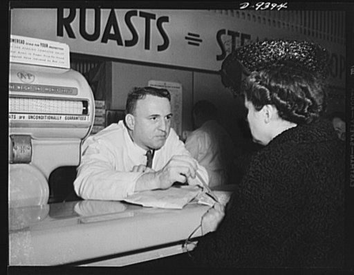 Meat rationing preview. Food editor of a woman's magazine shops for meat with red stamps. The "butcher" is William Nielander, Office of Price Administration (OPA) rationing executive