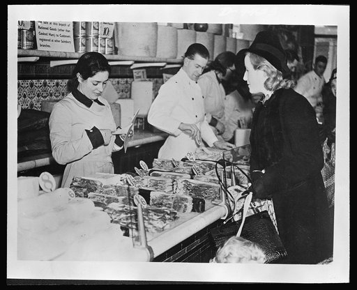 Food in Britain. A British suburban housewife surrenders coupons for her supply of bacon. Consumers may purchase no more than four ounces of bacon per week and not more than twenty-three cents worth of other meats