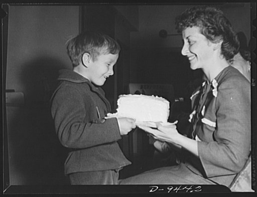 Wartime food demonstration. Peter Brusher, six-year-old son of a camouflage engineer, seems pleased with his mother's luck in winning half of the butterless, sugarless cake made by a wartime food demonstration nutritionist. Mrs. Brusher is one of the many American housewives who are attending simila