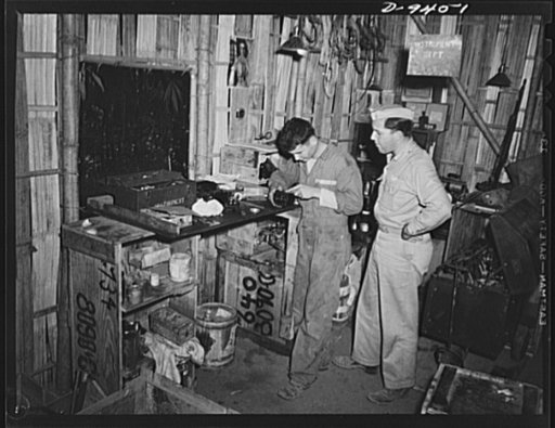 An American flying squadron in India. "You break it, we fix it," says Staff Sergeant William Denkowiez of Reinerton, Pennsylvania as he works on in the "instrument department" with Assistant Operations Officer Lieutenant R.J. Taylor, of Redlands, California, looking on. This bamboo-latticed work sho