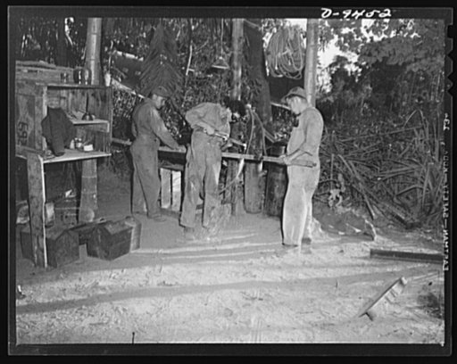 An American flying squadron in India. In their "open-air shop," American ground crew field mechanics, Sergeant Lapainski (left), Private Colden (center) and Private Groncy, weld a section of a plane girder. In background can be seen transport plane in "dispersal area"