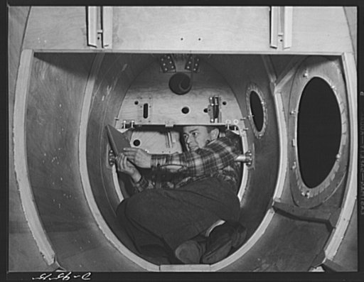 Production. BT-13A ("Valiant") basic trainers. A midget hard at work in the tail of a "Valiant" basic trainer at Vultee's Downey, California plant. He installs control wires and does other work that a normal-size person would not be able to get at. At the Downey plant is made the BT-13A ("Valiant") 