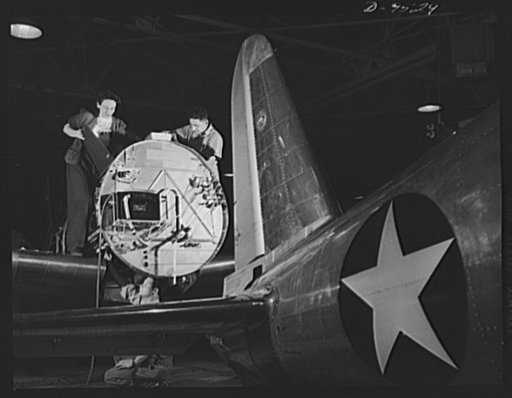 Production. BT-13A ("Valiant") basic trainers. Women and men work side by side at Vultee's Downey, California plant. Here electrical installations and control units for the motor of a "Valiant" basic trainer are being installed. At the Downey plant is made the BT-13A ("Valiant") basic trainer--a fas