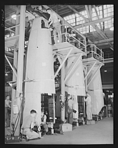 Production. A-31 ("Vengeance") dive bombers. Rear monocoque assembly. These huge vertical jigs are used at the Nashville Division of Vultee Aircraft Inc. for assembling the rear monocoque of the Vultee "Vengeance" dive bombers. A short stairway makes it possible for workers to reach easily all parts