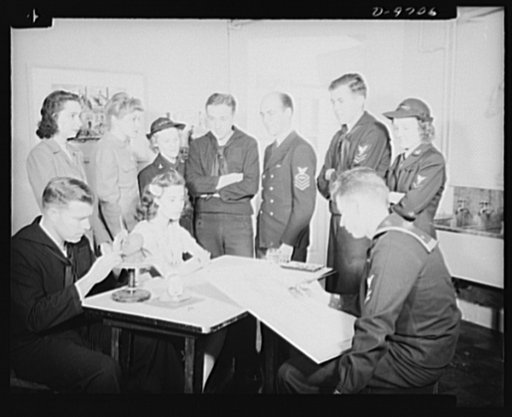 War workers. Social activities.  Sailor artist John Carey sketches a government girl in the art room of a Washington, D.C. United Service Organization (USO) center while sailor sculptor George Goepper (extreme left) models a caricature