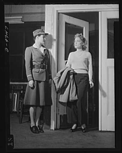 Safe clothes for women workers. Illustrating what the well-dressed women in search of a war job should NOT wear, pretty Eunice Kimball, Bendix Aviation worker, pauses at the entrance to the plant employment office where potential workers are interviewed. Though clothes may not make the woman, they A