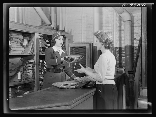 Safe clothes for women war workers. Applying for a standard uniform at the Bendix supply center, Eunice Kimball is given a company uniform to replace her own incorrect costume. Bendix Aviation Plant, Brooklyn, New York