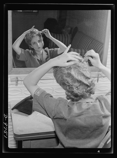Safe clothes for women war workers. The importance of keeping hair short and neat for industrial war work cannot be over-emphasized. Here Eunice Kimball, Bendix employee, gives a final pat to her newly-dressed hair. Bendix Aviation Plant, Brooklyn, New York