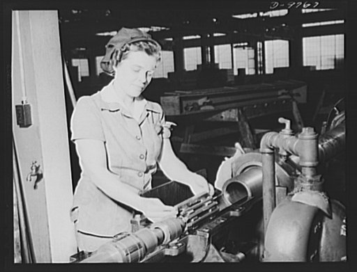 Production. 105 mm. howitzers. Lillian Goritschnig with two sons in the service, one overseas, and a husband ready to go into the service, inspecting the inside of a 105 mm. howitzer at the Milwaukee, Wisconsin plant of Chain Belt Company, with microbrand and also shot-changing the honing stone for 