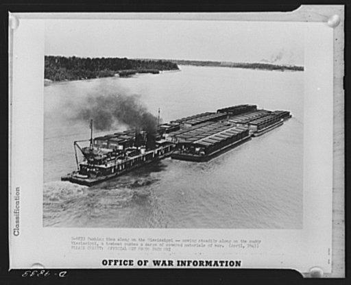 Pushing them along on the Mississippi. Moving steadily along the muddy Mississippi, a towboat pushes a cargo of covered materials of war