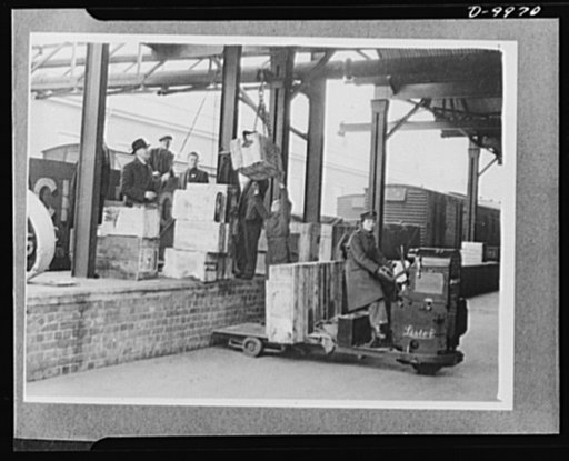 Lend-Lease to Britain. Cases of American spare parts arriving at an English ordnance center as part of a lend-lease shipment from the United States are moved to the stores for unloading. English girls, driving trucks, help with the task