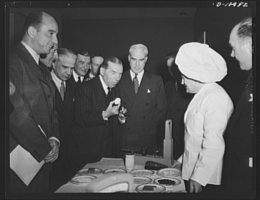 Lend-lease administrator Edward R. Stettinius, Jr., and guests at luncheon marking second anniversary of lend-lease, held March 11, 1943, at the Hotel Statler, Washington, D.C., look on as Representative Sol Bloom, chairman of the House Committee on Foreign Affairs, inspects an egg. Dehydrated food,