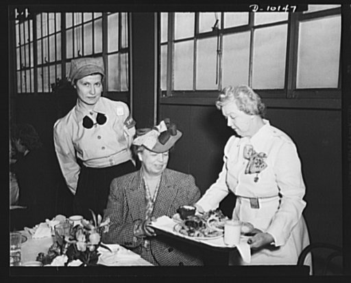Mrs. Roosevelt is served a Victory lunch on her visit to General Motors' Eastern Aircraft Division in Linden, New Jersey. Consisting of a small steak, two vegetables, salad, enriched breads, custard and a glass of milk, this highly nutritious lunch is provided war workers for forty-seven cents in th