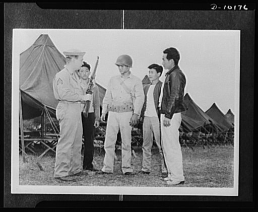Japanese-American volunteers. With battle helmet on his head and ammunition belt about his waist, Kauai-born Mitsuru Doi, eighteen, the first AJA [Americans of Japanese ancestry] volunteer to be inducted and given a uniform is taught the rudiments of rifle drill by Sergeant John H. Chynoweth, acting