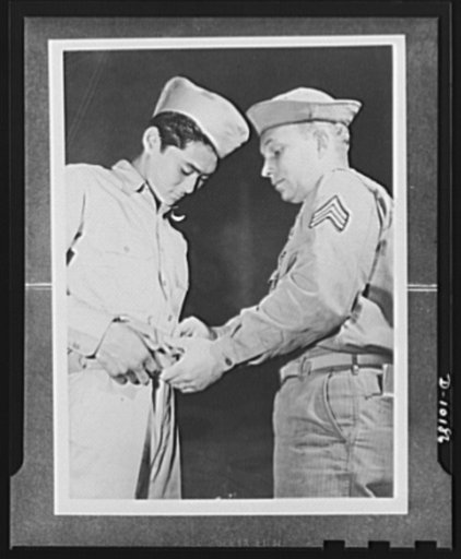 Japanese-American volunteers. First AJA [Americans of Japanese ancestry] volunteer to put on the uniform of the U.S. Army, Mitsuru Doi, eighteen, of Lihue, Kauai, is shown how to buckle on his ammunition belt. Doing the showing is Sergeant John H. Chynoweth, acting first sergeant of the provisional 