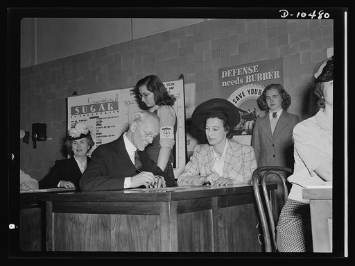 Sugar rationing. What every householder will know! Mrs. Leon Henderson, wife of the Office of Price Administration's (OPA) head, goes through the routine of registering for her sugar rationing book, assisted by Dr. Elmer S. Newton, superintendent of Western High School, Washington D.C. Nationwide re