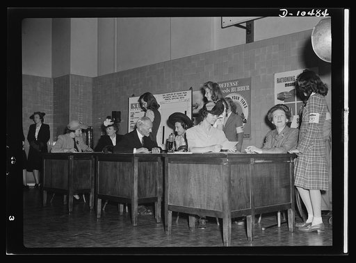 Sugar rationing. Three prominent ladies learn how to register for their sugar rationing books. Mrs. Henry Wallace, Mrs. Leon Henderson and Mrs. Bennett Clark (seated left to right, facing camera) learn how to fill in their ration books from teachers and pupils at Western High School, Washington, D.C