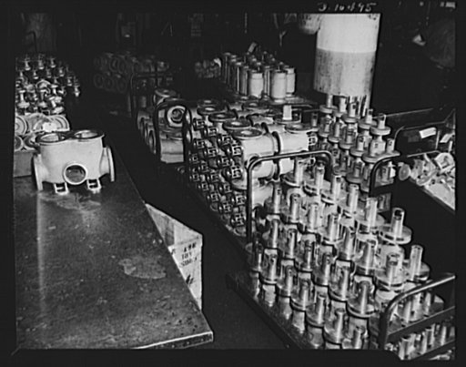 Brooklyn, New York. Dollies, carrying newly-machined engine parts, being moved in and out of the shipping room of a factory engaged in subcontracting work for aviation, shipbuilding and radio manufacturing concerns. This factory previously made oil burner equipment