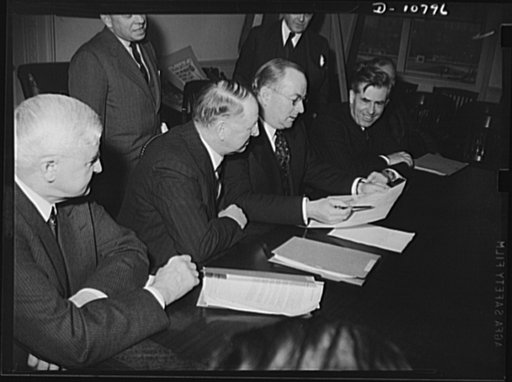 The following members and alternates attended the first meeting of the War Production Board (WPB), held January 20th, 1942, in the conference room of the new Social Security building. Seated, left to right: Jesse Jones, Federal Loan Administrator; Frank Knox, Secretary of the Navy; Donald M. Nelson,