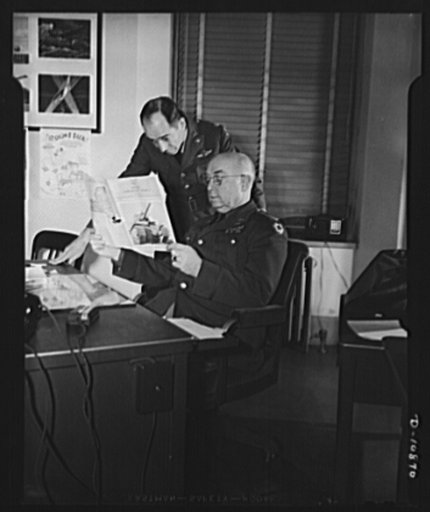 Air Corps procurement OPM  news, New York. Photo shows Colonel Roy M. Jones (seated) wuth Lieutenant Colonel C.S. Johnson of the Army Air Corps ordnance procurement looking over the latest issue of OPM news to familiarize small manufacturers with the facilities of division of contract distribution w