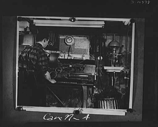 Conversion. From garage to defense workshop. One of Carell's workmen at a lathe in this basement war workshop. The lathe has a tailstock turret attachment which holds several tools so that one operation can follow another in quick succession, as in the factory production