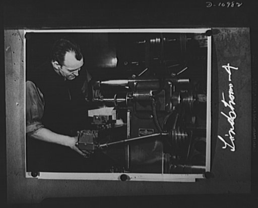 Conversion. From garage to defense workshop.  Lindstrom shown working at a small milling machine in his garage shop. This, like most of his other equipment, is comparatively new and modern