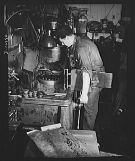 Grinding bullet dies. Here, in the shop of a small manufacturer of saws and knives in downtown New York City, a workman grinds bullet dies to close tolerances on a special surface grinding machine. This fully converted shop is carrying out heat treating, straightening and surface grinding work on hu