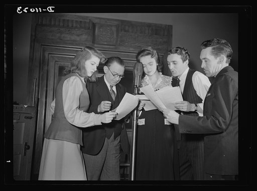 Gathered around the microphone during rehearsal are (left to right) Virginia Moore, Colonel Charles Ferris, Doris McWhirt, John Flynn, and Robert Pollard. They make transcriptions four times a month for the series of radio shows, "You Can't Do Business With Hitler," which is written and produced by 