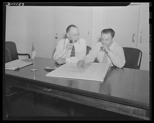 Donald M. Nelson (left), Chairman, War Production Board (WPB), and Leon Henderson, Administrator, Office of Price Administration (OPA) and Director, Civilian Supply Division of the Office of Production Management (OPM), member of the Supply Priorities and Allocations Board; conferring in Washington,