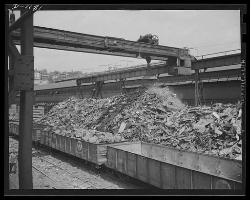 Steel manufacture. Back into production go these carloads of scrap metal. The melting of alloy steels for defense work requires that steel mill scrapyards such as this be constantly filled. The overhead magnet deposits the scrap in a loader which carries it to the open hearth furnace. About fifty pe