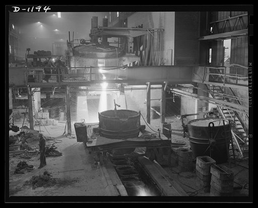 The molten stream pouring from the thirty-five ton electric furnace is slag-waste material melted down during the process of refining. It is composed largely of limestone, which carries with it various other impurities in the metal. In the foreground is a huge ladle into which the molten steel will 