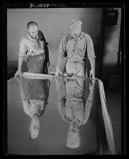 Steel manufacture, Allegheny-Ludlum. These inspectors are trained to look for even the slightest imperfection in sheets of stainless such as this. All the high quality steel steel used in defense production is inspected and thrown back into the furnaces in case of any imperfection