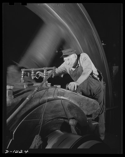 Steel manufacture, Allegheny-Ludlum. Engineers must be alert at all times, to see that the bearings coupling the mill engines are kept oiled. Negligence might mean long delays in steel production. The engineer above is adjusting the valve of the oil line to increase the flow (note the huge fly-wheel