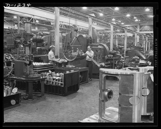 Tank manufacture (Chrysler). Traveling overhead hoists are used throughout the huge Chrysler tank arsenal in Detroit, for moving heavy castings from one production operation to another. These workers are removing the rotor casing for a 75 mm gun turret from a machine which grinds the outside rim. Th
