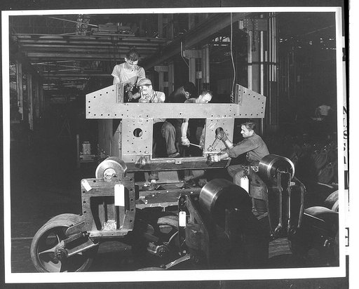 Tank manufacture (Chrysler). Every one of the 10,000 workers at the huge Chrysler tank arsenal in Detroit must know his job perfectly in order that there is no time lost as these twenty-eight ton M-3 tanks move on down the assembly line. These men are completing the final assembly of the rear hull p