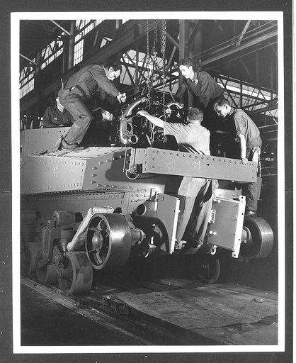 Chrysler tank arsenal. Installing the power plant is a ticklish operation. These workers are lowering a 400 horsepower Wright Whirlwind aviation engine into an M-3 tank and they are taking care to insure that each fitting and connection may be made within a few seconds after the motor has been place