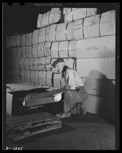 Army truck manufacture (Dodge). Tons of tarpaulin are required for covering certain types of Army trucks. Worker above is unpacking tarpaulin, and a very small portion of the huge stock always carried on hand is shown in the background