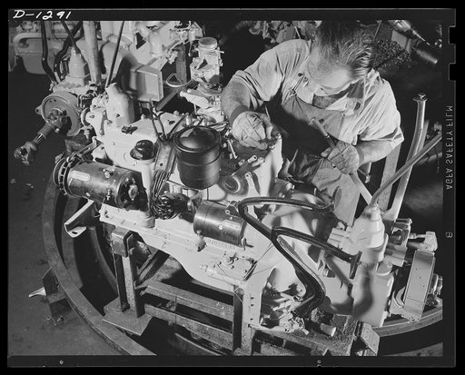 Army truck manufacture (Dodge). An expert installs the accessories for the engine of Dodge Army trucks that are specified by Army regulations. With skill and accuracy craftsman shown above attaches oil filters, air cleaners, hoops up spark plug wires and sees that all are properly coordinated and in