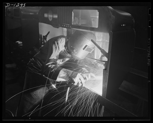 Army truck manufacture (Dodge). A veritable cascade of sparks fly when the arc welder fuses together toe risers in the front section of a Dodge army truck cab assembly