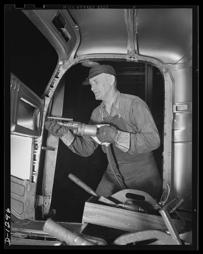 Army truck manufacture (Dodge). A veteran factory worker, typical of the many seasoned craftsmen in the automobile industry, busily engaged in handling doors on the cab of an army truck