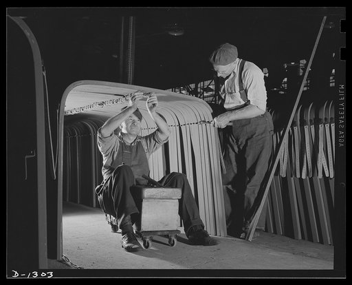Army truck manufacture (Dodge). Wood workers, too, have their place in building trucks for the U.S. Army. These men are assembling brackets and metal strips to the wood bows that support a ridge pole which extends the entire length of the body and gives added strength and support to the bows