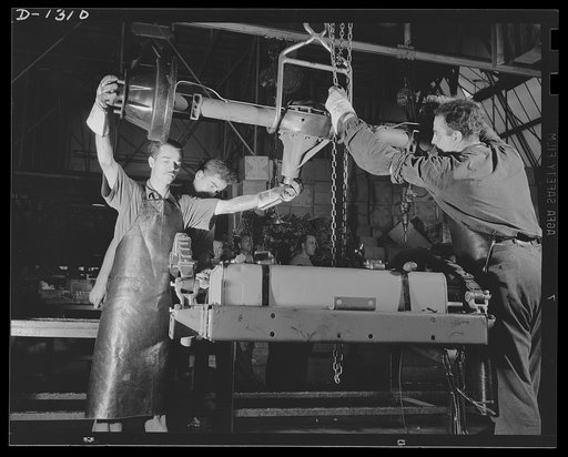 Army truck manufacture (Dodge). Overhead conveyors eliminate heavy lifting and facilitate rapid production of trucks for the U.S. Army in the Dodge truck plant in Detroit. Shown above are workmen lowering the heavy rear axle of an army truck to its place in the chassis assembly by means of a special