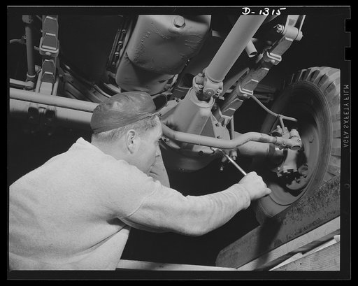 Army truck manufacture (Dodge). A defense worker checking the front axle assembly of a Dodge Army truck just before it moves off the production line