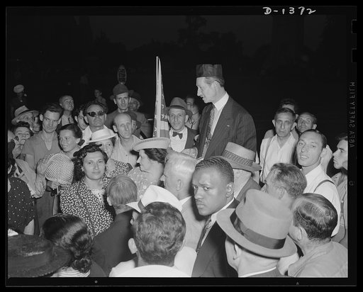 The four freedoms. The people gather on a million street corners to discuss a million problems. Only in a democracy are they free to discuss the affairs of their nation and the affairs of the world. Only in a democracy would we find this free mingling of a dozen different races. The scene is Columbu