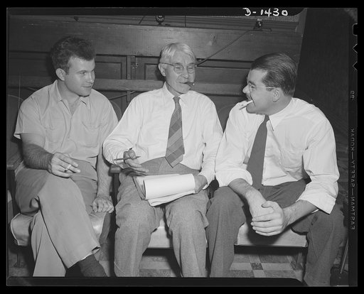 Carl Sandburg famous for his lusty humor, is telling characteristic anecdote to Guy Bolte, motion picture director, on his left, and Phillip Martin, film editor, on his right. This photograph was made while Mr. Sandburg was working on the commentary for "Bomber," national defense motion picture just