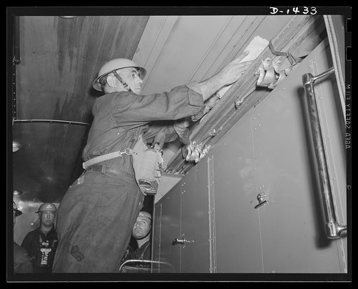 Civilian defense. Removing blankets and stretchers from the special compartment in the New York Emergency Service truck. The lower compartment contains a portable searchlight of 1000 candle power