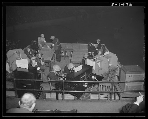 In the left foreground are four operators at telephones, one connected with the first aid center, one with the decontamination squads, one with the disaster units and the fourth with the emergency service division. There is a twenty-six watt transmitter and receiver to maintain communcations with un