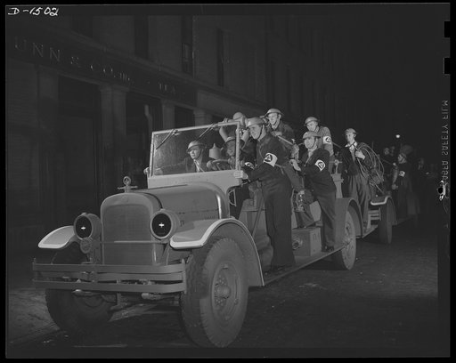 Civilian protection. These auxiliary firemen will play an important part in our civilian defense in the event of air raids on American cities. Here they are going out on a practice "emergency call." The truck is a regular fire department hose wagon, painted battleship gray to reduce visibility and e
