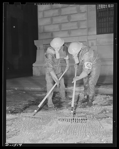 Civilian protection. Completely enclosed, just like deep sea divers, to make certain that none of the blistering gas vapors will seep through to their skin, these members of a decontamination squad are spreading a mixture of sand and chloride of lime to neutralize an area which has been attacked wit